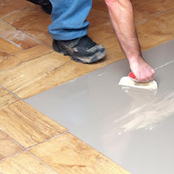 Man applying a primer to a tiled floor